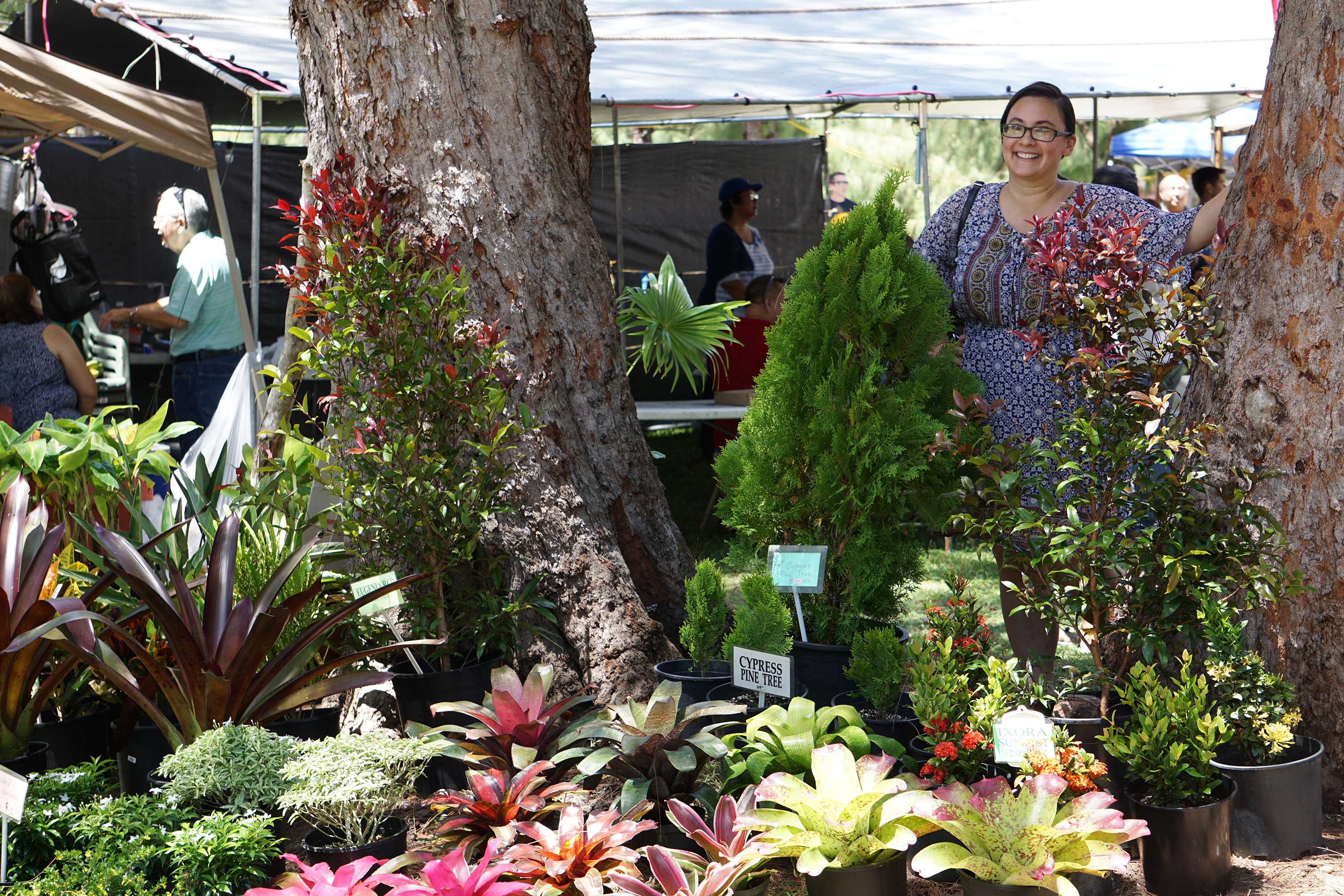 Woman standing among tropical plants at the Talofofo Banana Festival plant market in Guam.