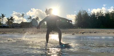 Skim Boarder coasting along the waves in Guam